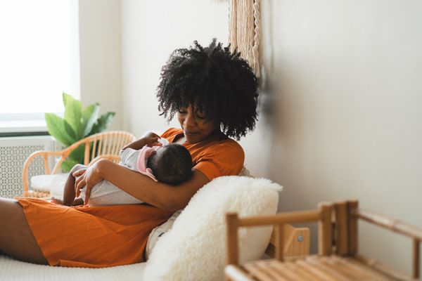 A mother breastfeeds her baby in the bedroom in the evening