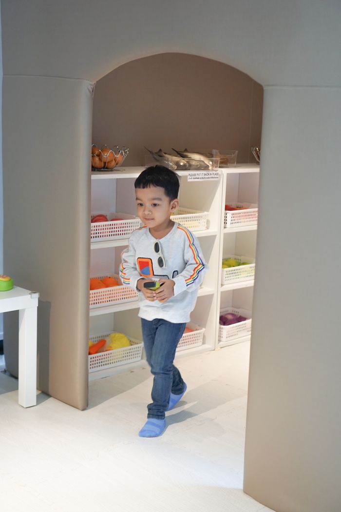 A toddler walks through a bright playroom full of toys
