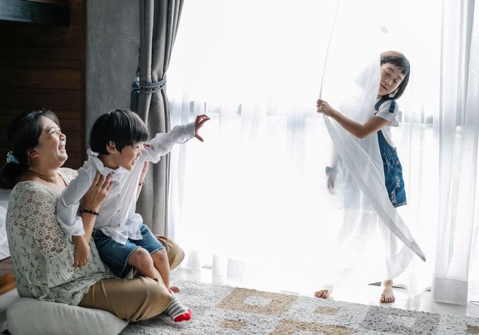 A laughing mother plays with her children in a sunny room