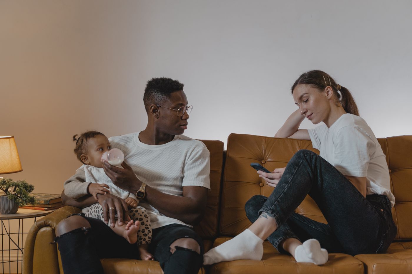Parents relax on the sofa with their baby and a phone