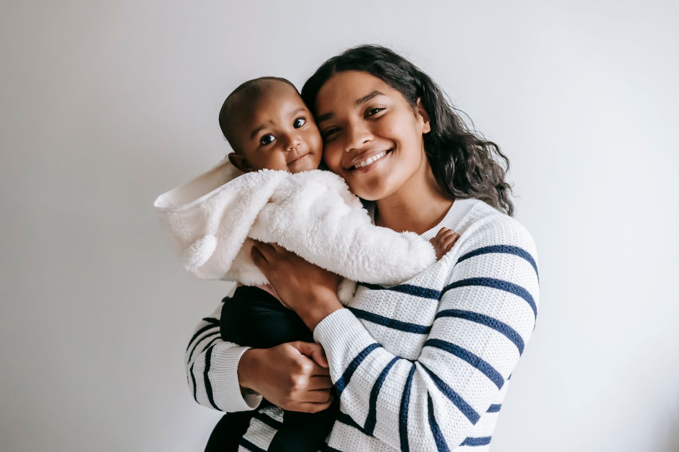 A smiling mother holds her laughing baby close in a bright room