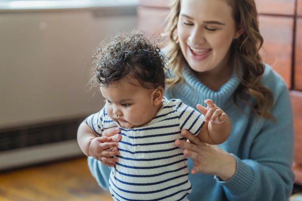 A mother helps her baby take a first step