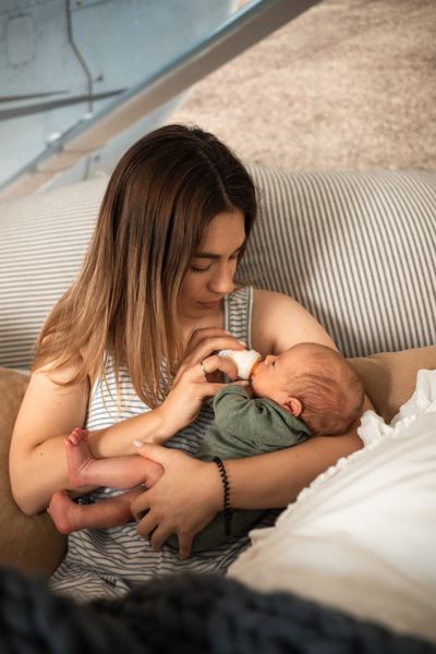 A mother bottle-feeds her newborn