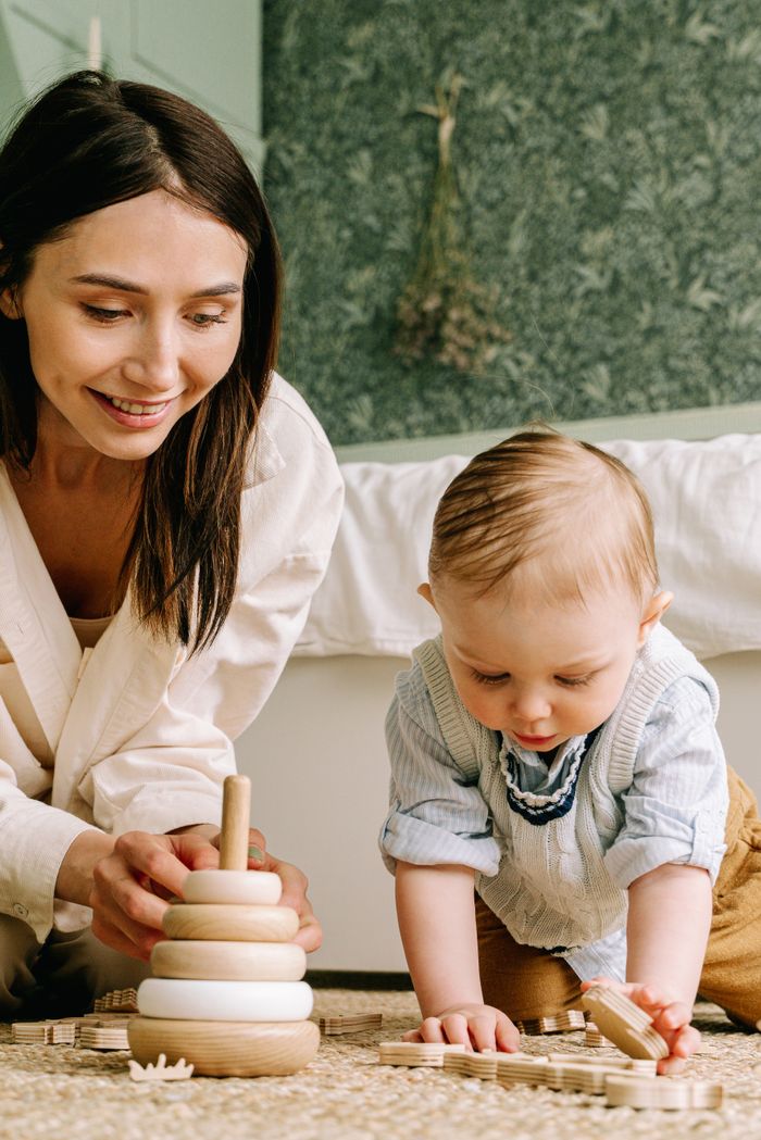 A mother and baby play with wooden toys